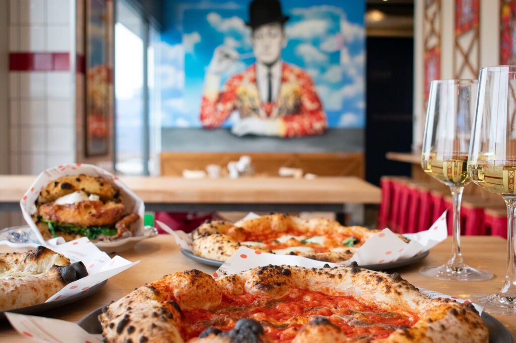 Pizzas in front of blue mural of man at Stellina Pizzeria